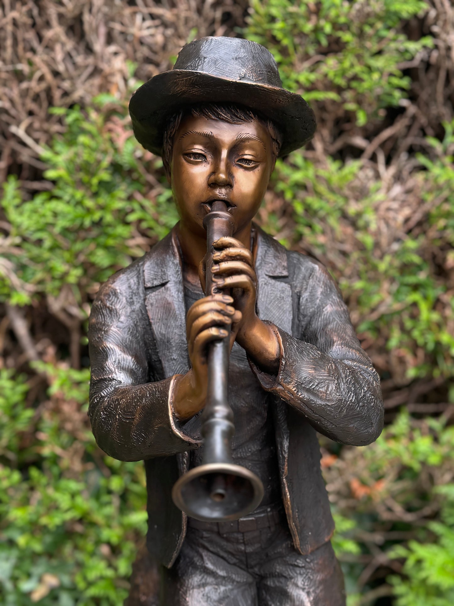 Estátua de bronze de menino com flauta.