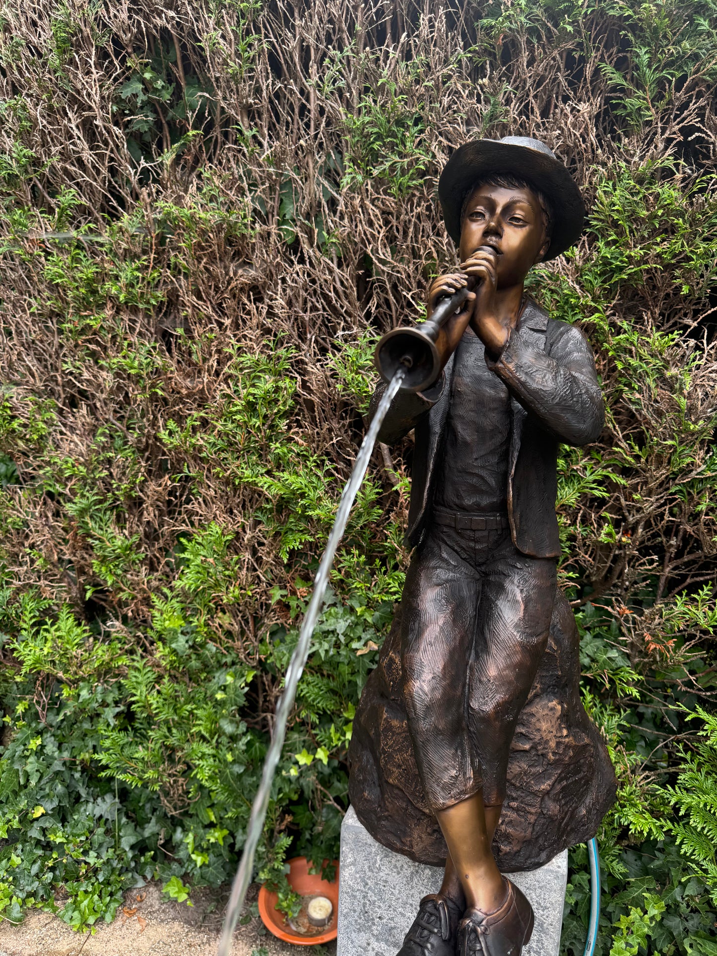 Estátua de bronze de menino com flauta.